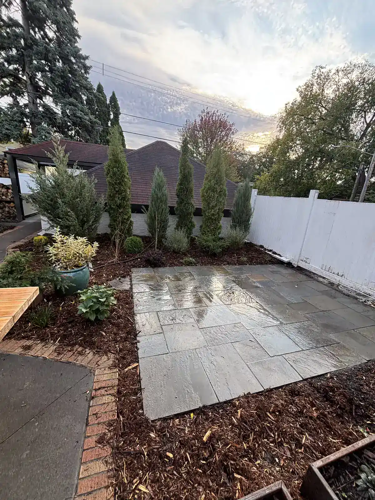 Completed full-color bluestone patio with brick border and arborvitae screening in Edina, MN
