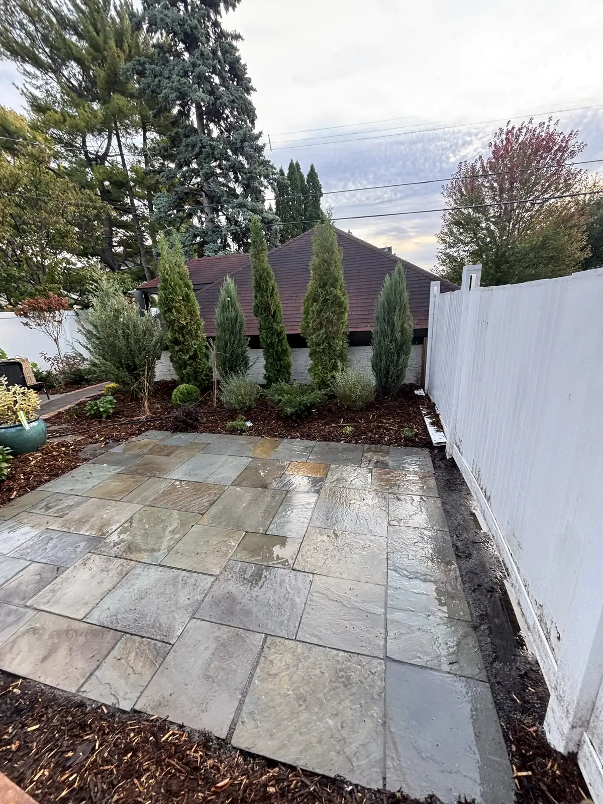 Wide view of finished bluestone patio with privacy plantings and fence in Edina, MN