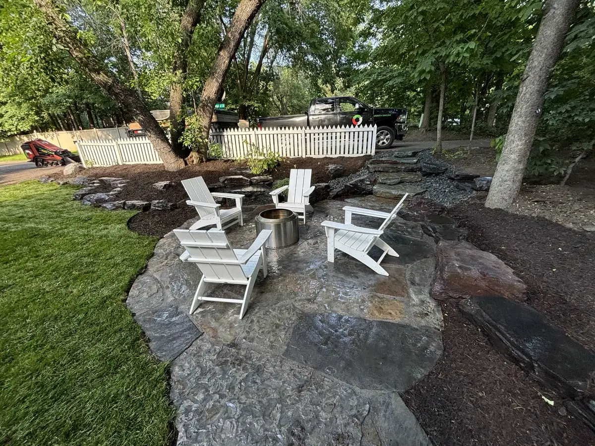 Natural stone fire pit area with Adirondack chairs in Edina backyard