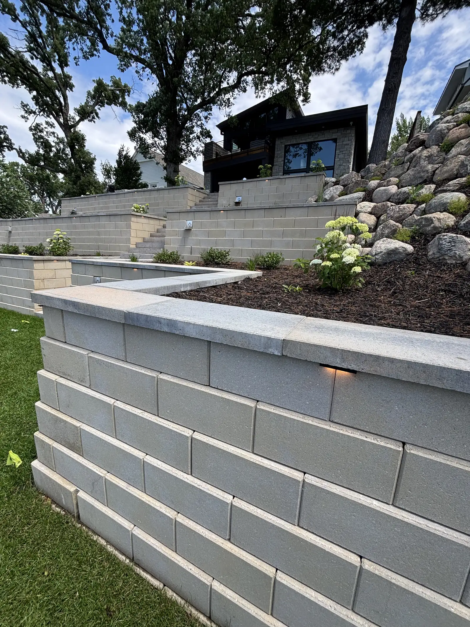 Multi-tier smooth-faced retaining wall with LED lighting and landscape plantings in Excelsior, MN