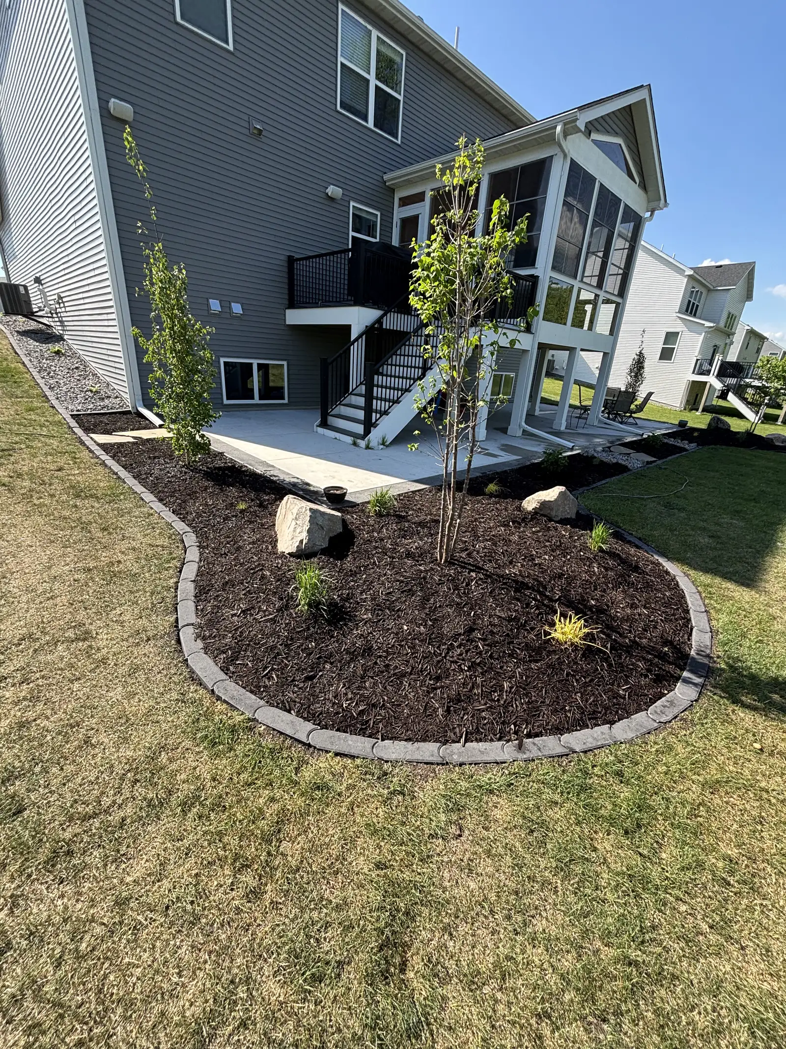 Decorative dry creek bed drainage feature with river rock and boulders