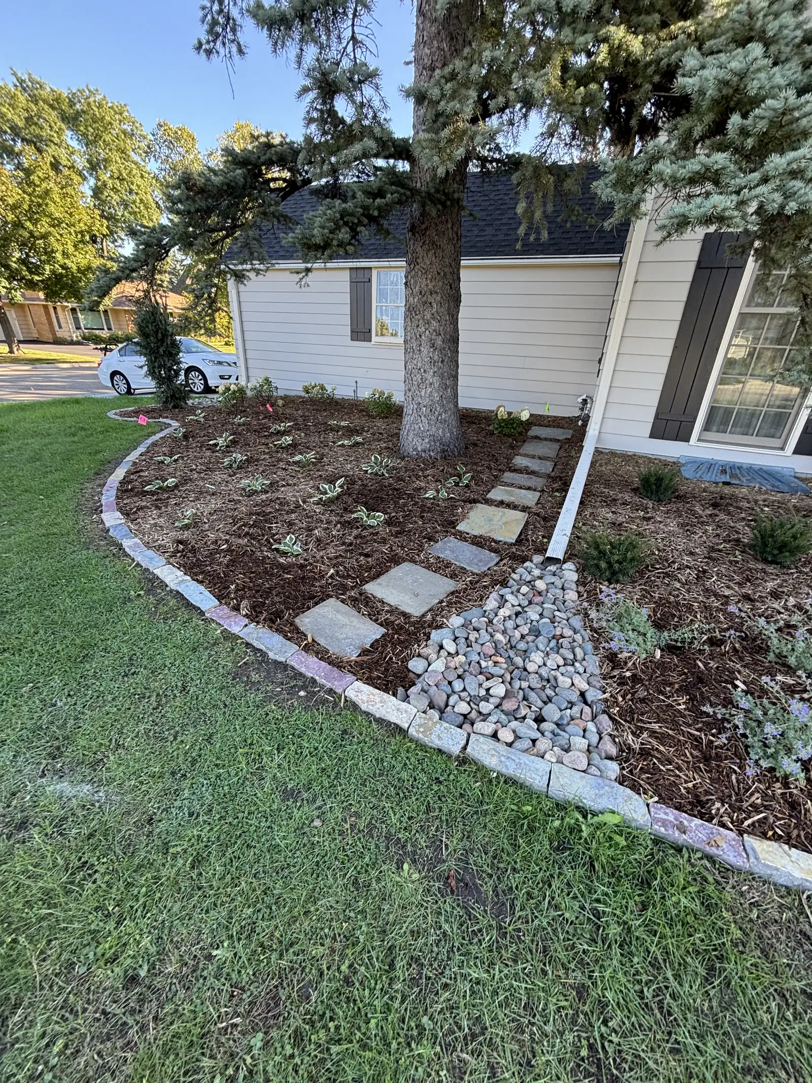 Stone staircase with integrated retaining walls connecting house level to yard in Shorewood