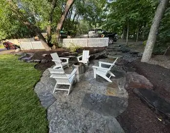 Modern horizontal slat privacy screen with stone base on a patio