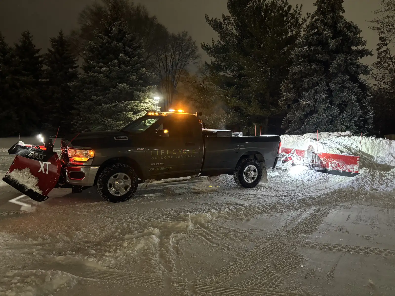 Lifecycle Outdoor Services plow truck with Boss snowplow actively plowing a driveway at night during a Minnesota snowstorm