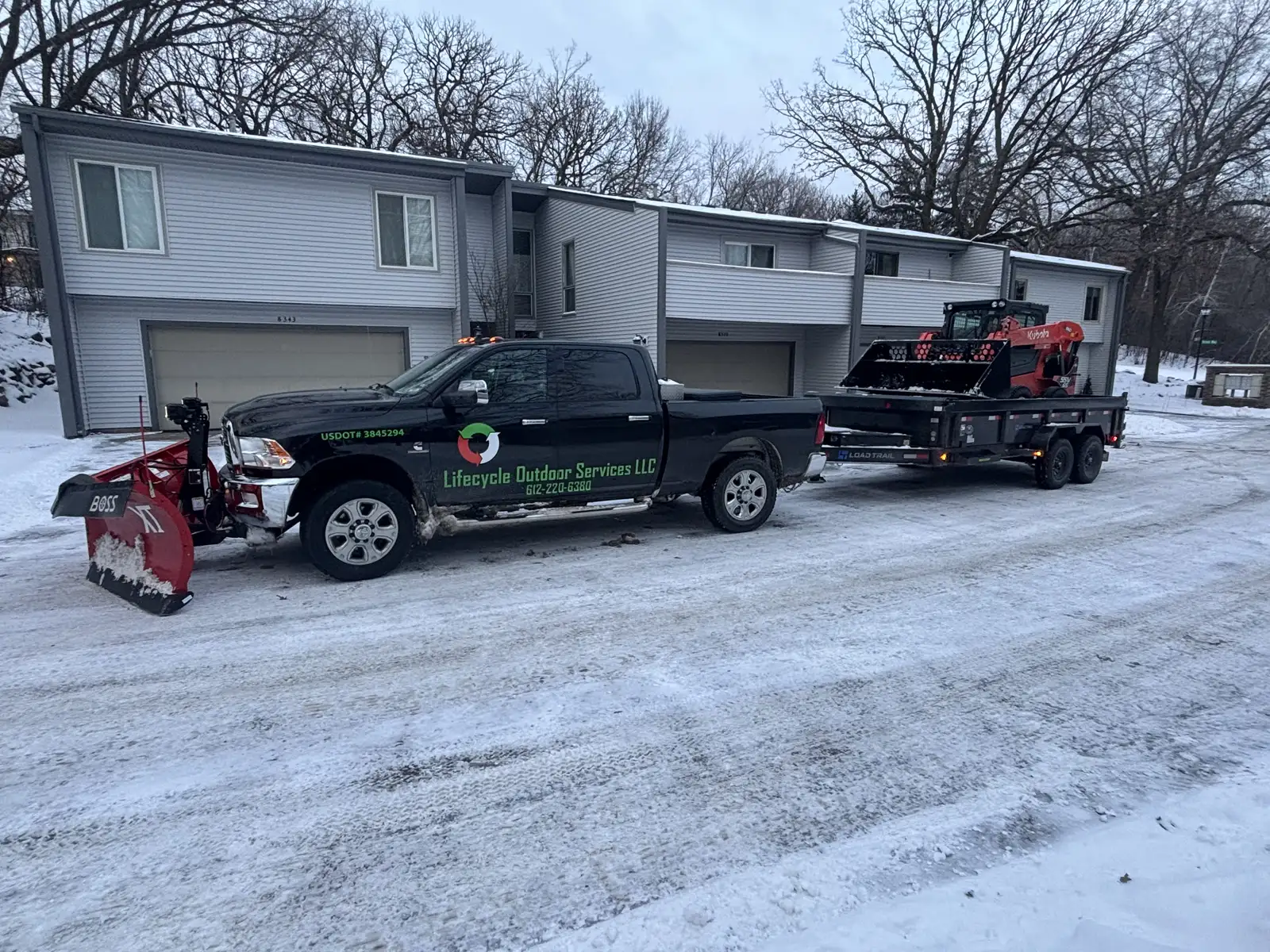 Lifecycle Outdoor Services branded plow truck with Boss snowplow and equipment trailer in snowy residential neighborhood