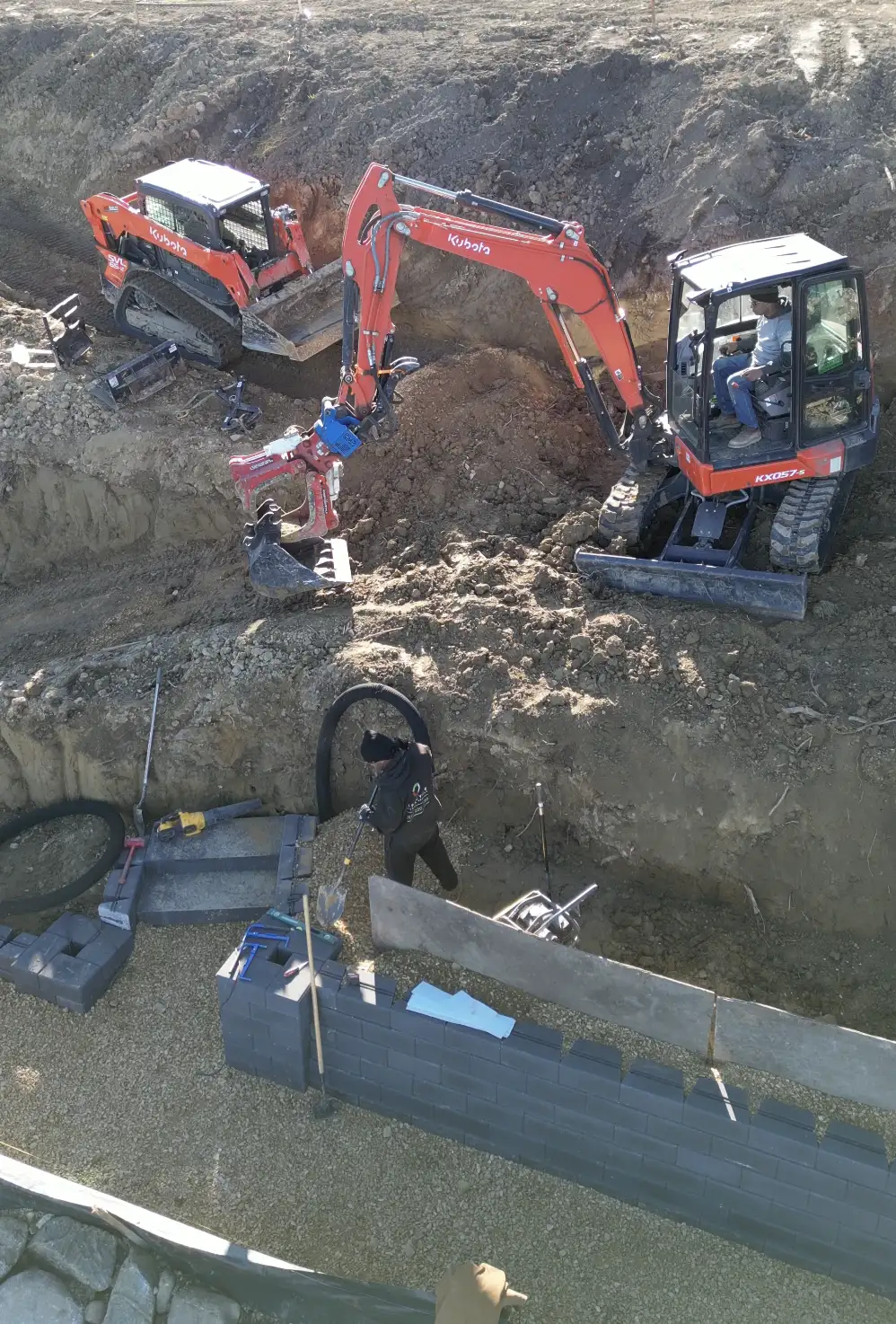 Excavation with drainage pipe installation at lakeside property using dual Kubota excavators