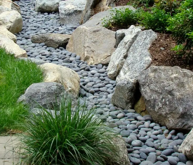 Decorative dry creek bed with smooth river rocks and boulders for residential stormwater drainage